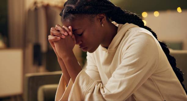 Black girl, worship or pray on sofa in home for solace or devotion, spiritual connection and wellness gratitude to god. Woman, eyes closed and prayer to higher power for praise or hope.