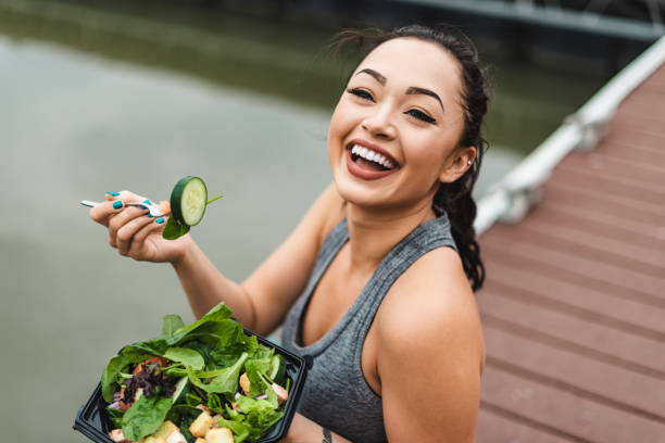 fitness woman eating an healthy salad and smiling