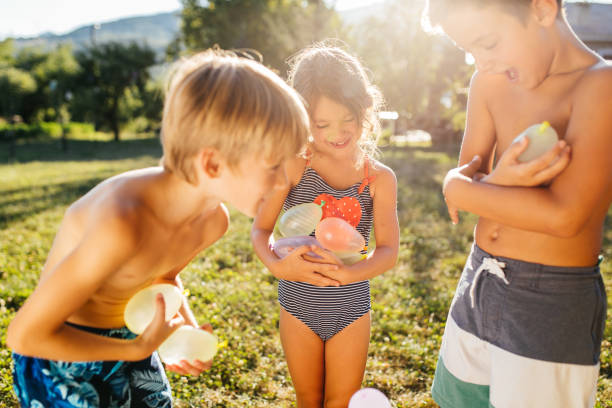 Group of children having fun in the yard with , fighting with water bombs with balloons filled with water, and refreshing on a hot summer day